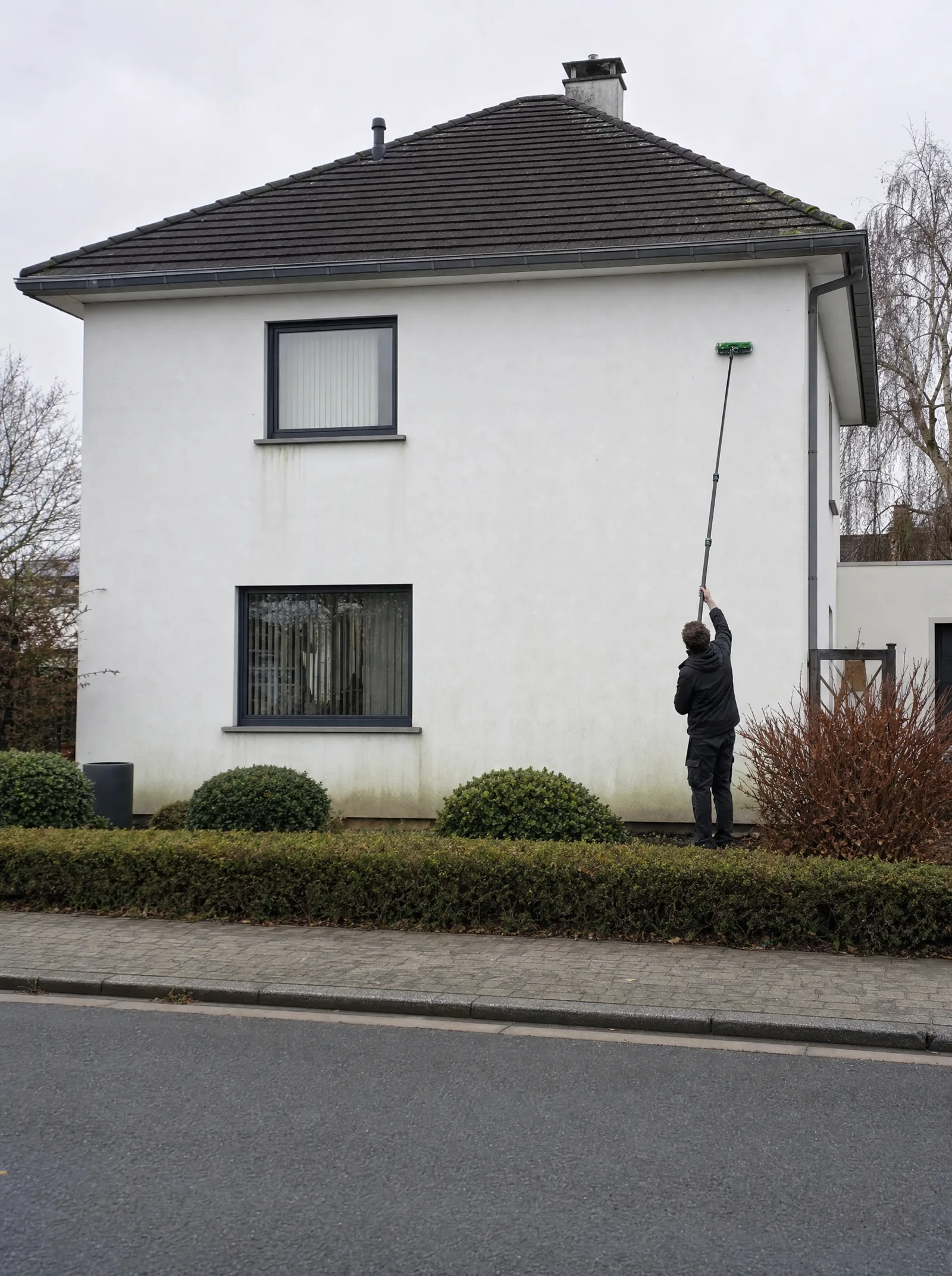 Topgevel in crepi met groene aanslag, tijdens de reiniging vanaf de grond